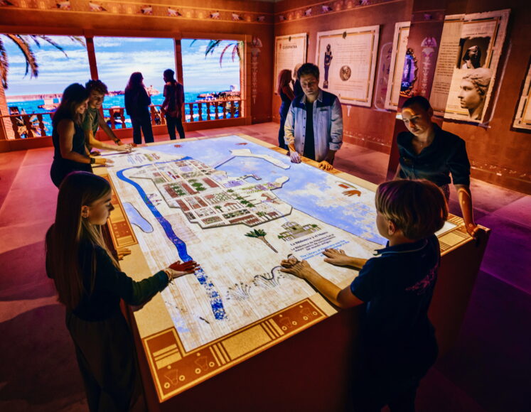 9 Cleopatra The Experience - people gathered around an interactive map in the exhibition